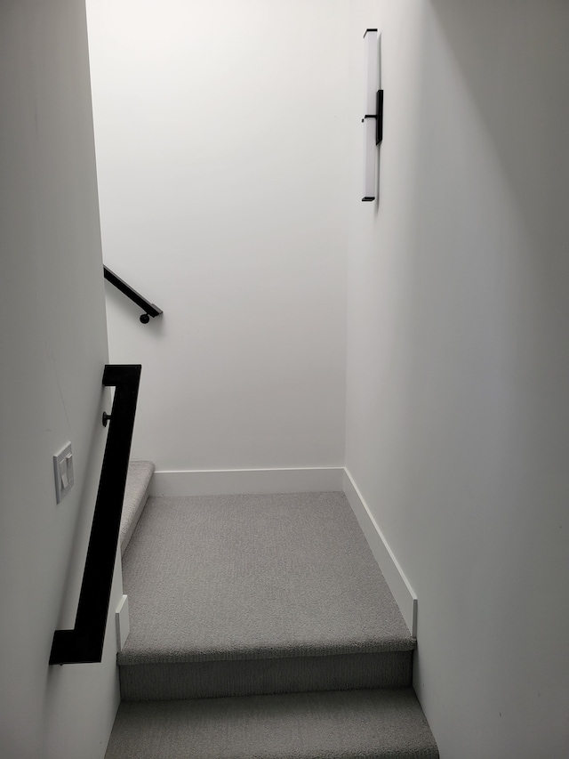 staircase featuring baseboards and carpet