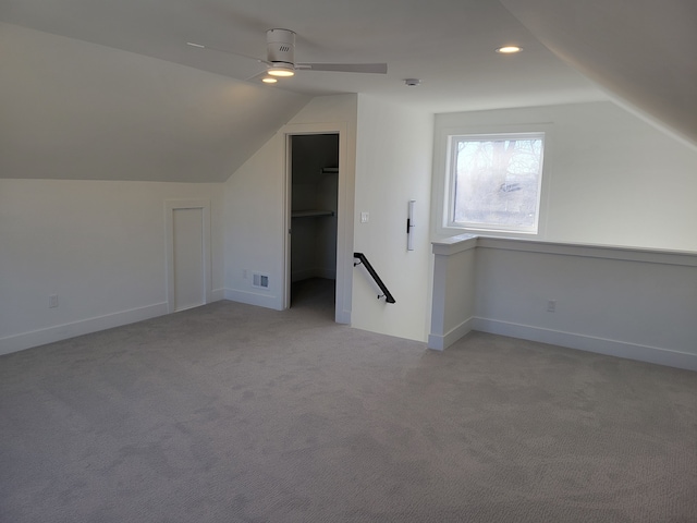 additional living space with visible vents, baseboards, lofted ceiling, light carpet, and a ceiling fan