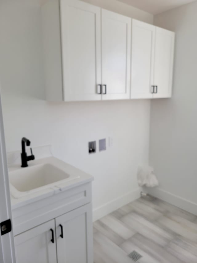 laundry room featuring washer hookup, cabinet space, baseboards, and a sink