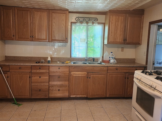 kitchen featuring light tile patterned floors, white gas range oven, and sink