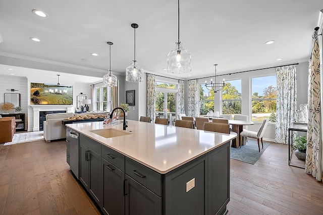 kitchen with dark hardwood / wood-style flooring, sink, decorative light fixtures, a center island with sink, and a chandelier