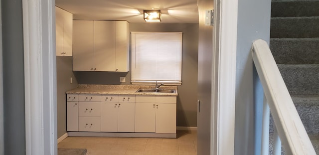 kitchen featuring white cabinets, light tile patterned floors, and sink