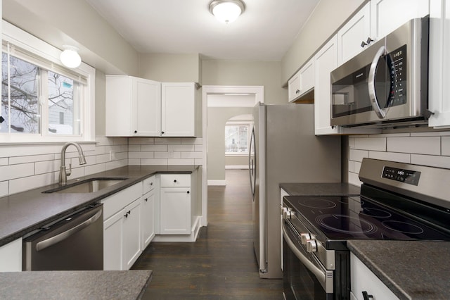 kitchen featuring dark hardwood / wood-style flooring, tasteful backsplash, stainless steel appliances, sink, and white cabinets