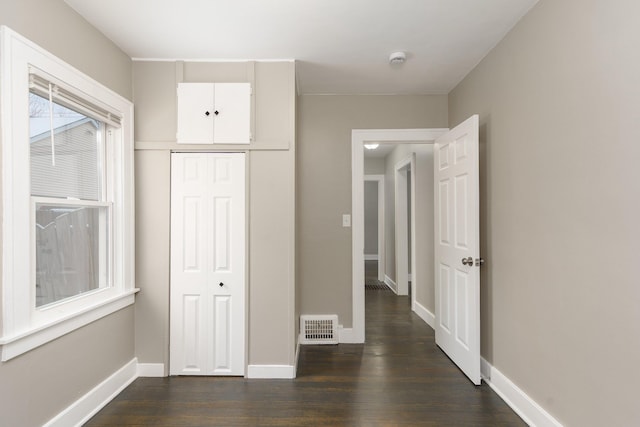 unfurnished bedroom with dark hardwood / wood-style floors and a closet