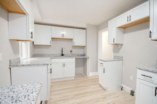 kitchen featuring white cabinetry, sink, and light hardwood / wood-style flooring