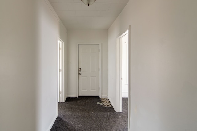 hallway featuring crown molding and dark carpet