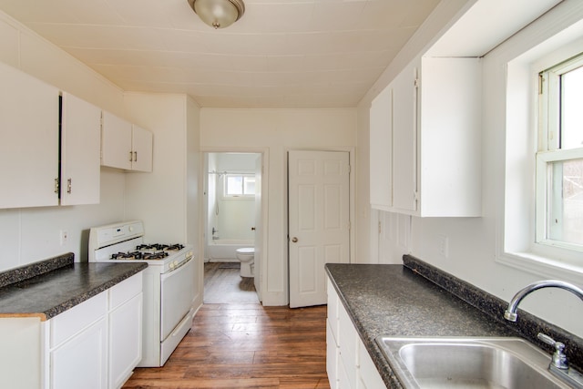 kitchen featuring white cabinets, white gas range oven, dark hardwood / wood-style floors, and sink