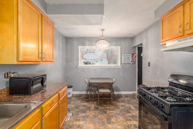 kitchen featuring pendant lighting, black gas range, dark stone counters, and an inviting chandelier