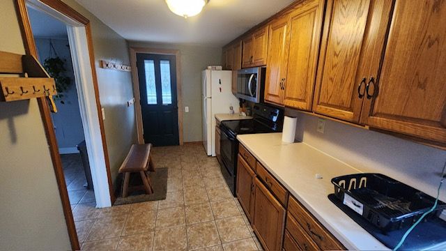 kitchen with electric range, white fridge, and light tile patterned flooring