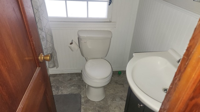 bathroom featuring wood walls, sink, and toilet