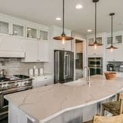 kitchen featuring white cabinets, hanging light fixtures, a kitchen bar, and a spacious island