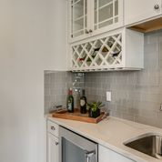 bar featuring sink, white cabinets, and backsplash