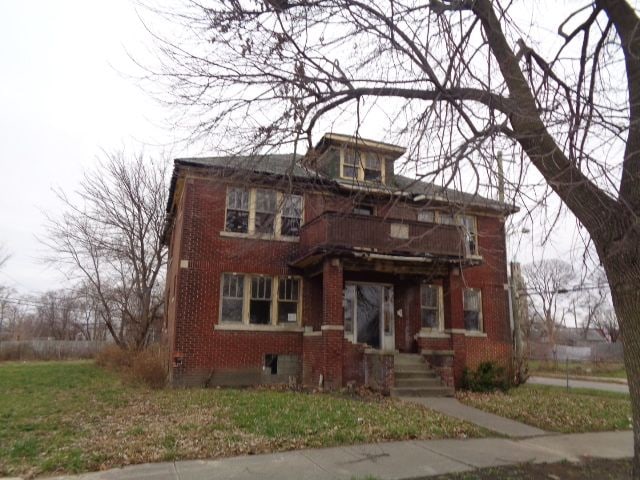 view of front of home featuring a balcony and a front lawn