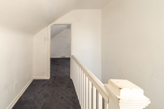 corridor featuring vaulted ceiling and dark colored carpet