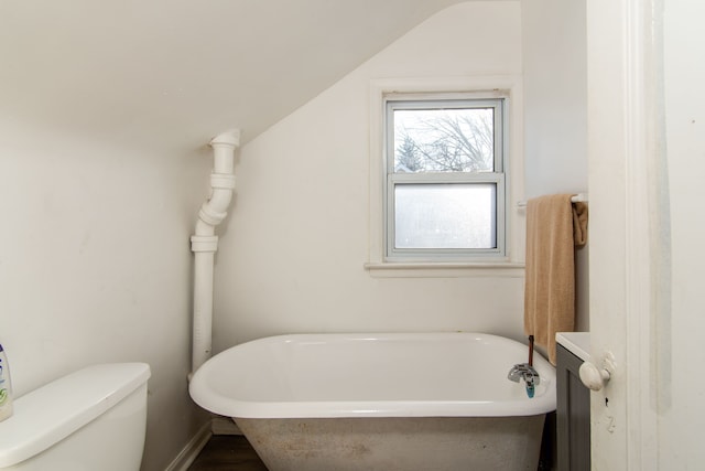 bathroom with a bathing tub, lofted ceiling, and toilet