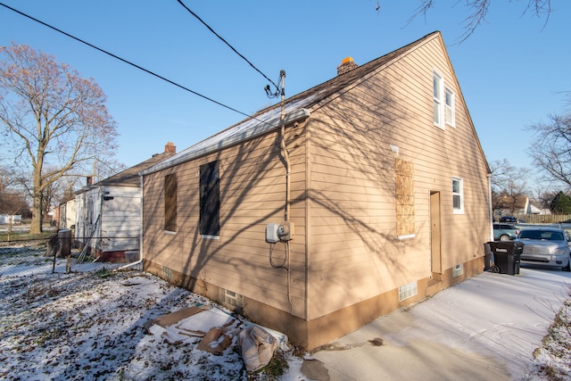 snow covered rear of property featuring a patio