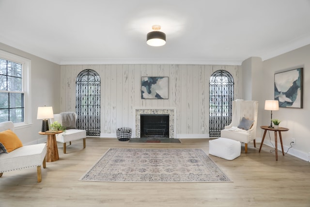 sitting room featuring ornamental molding, light hardwood / wood-style floors, and wooden walls