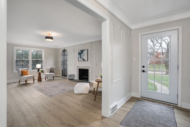 entrance foyer featuring crown molding, a large fireplace, and light hardwood / wood-style flooring