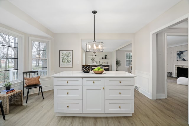 kitchen with white cabinets, a kitchen island, hanging light fixtures, and light hardwood / wood-style flooring