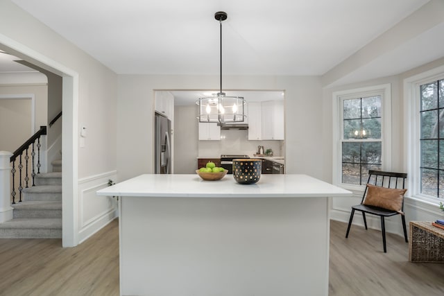 kitchen featuring plenty of natural light, white cabinets, pendant lighting, and light hardwood / wood-style flooring