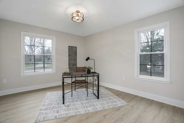 home office with light hardwood / wood-style floors and a healthy amount of sunlight