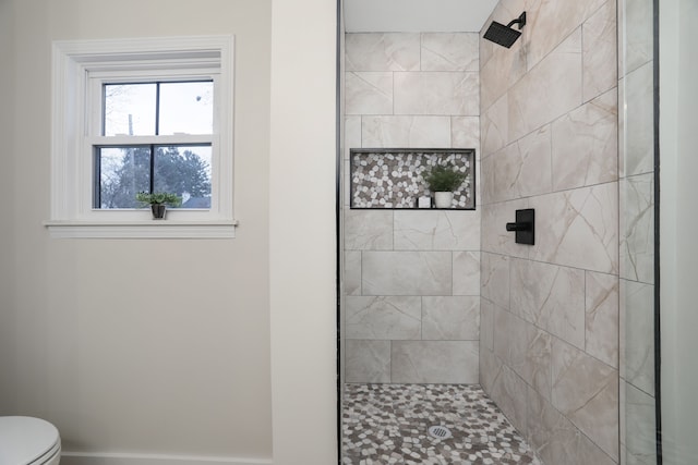 bathroom featuring a tile shower and toilet