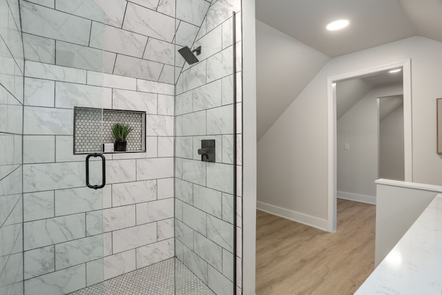 bathroom featuring wood-type flooring, walk in shower, and lofted ceiling