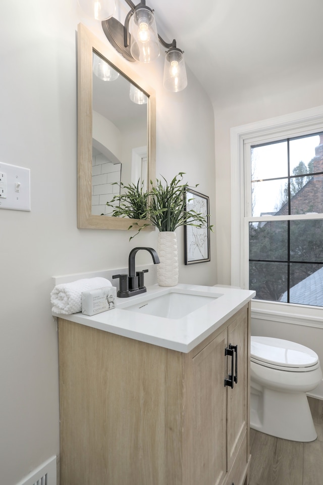 bathroom with hardwood / wood-style floors, vanity, and toilet