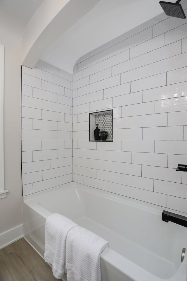 bathroom with hardwood / wood-style floors and tiled shower / bath combo