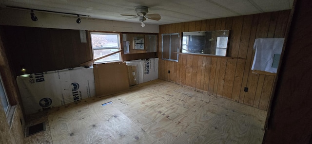 empty room featuring ceiling fan and wooden walls