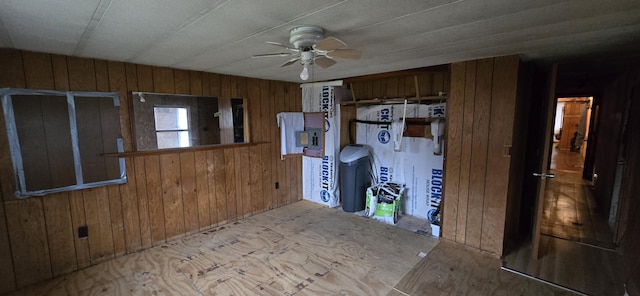 interior space featuring ceiling fan and wooden walls