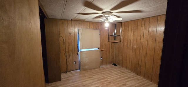 interior space with wooden walls, light hardwood / wood-style flooring, and ceiling fan