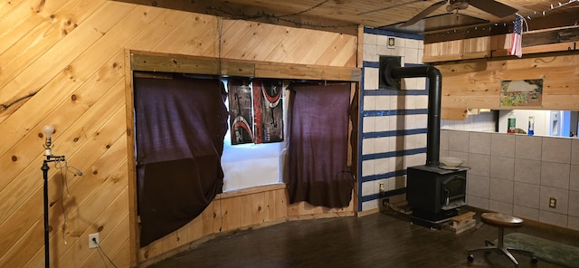 basement with ceiling fan, wood walls, and a wood stove