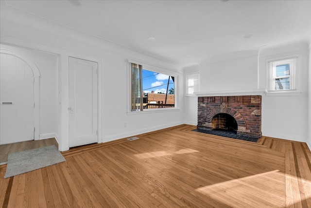 unfurnished living room featuring a fireplace, a healthy amount of sunlight, and hardwood / wood-style flooring