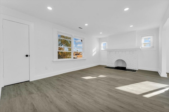 unfurnished living room featuring dark hardwood / wood-style flooring and a brick fireplace