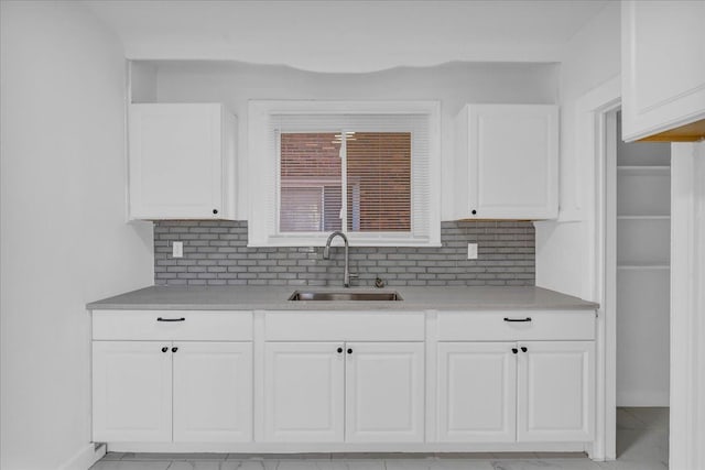 kitchen with white cabinets, decorative backsplash, and sink