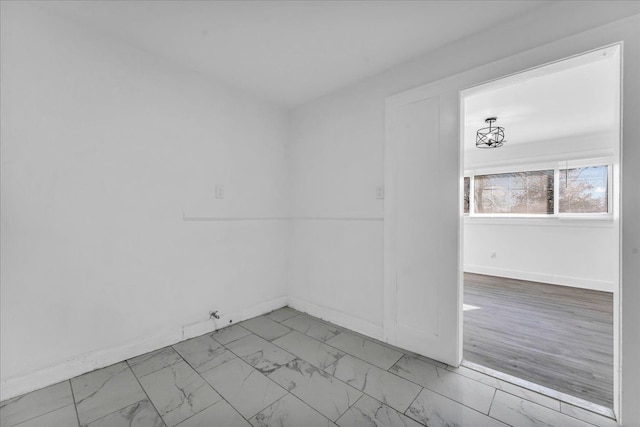 empty room with light wood-type flooring and a chandelier