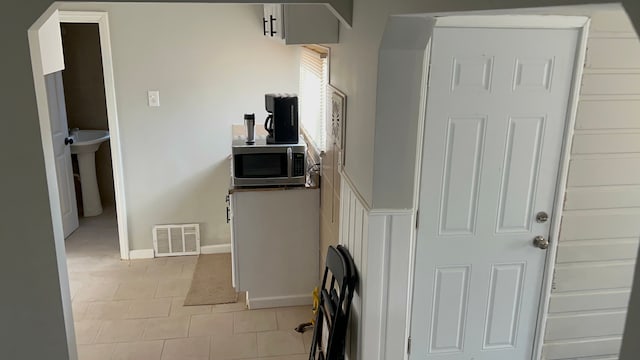 hallway featuring sink and light tile patterned flooring