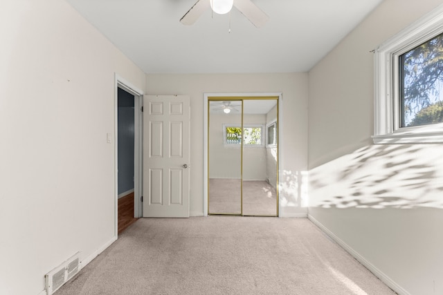 unfurnished bedroom with light carpet, a closet, and ceiling fan