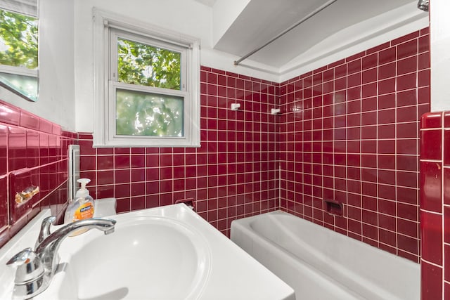 bathroom featuring tub / shower combination, sink, and tile walls