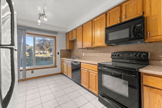 kitchen with backsplash, sink, light tile patterned floors, and black appliances