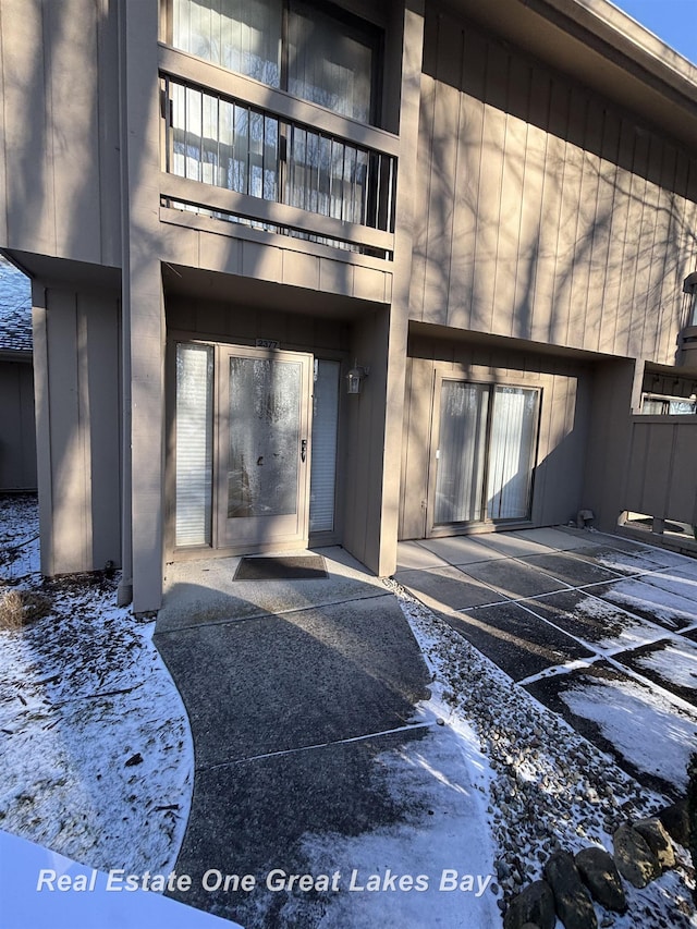 2377 Bay Woods Ct, Bay City, MI 48706 - snow covered property entrance featuring a balcony, a patio, and uncovered parking