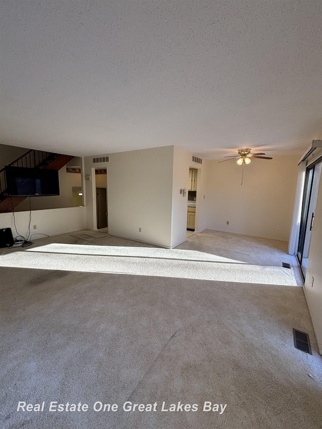 unfurnished living room with light carpet, ceiling fan, and a textured ceiling