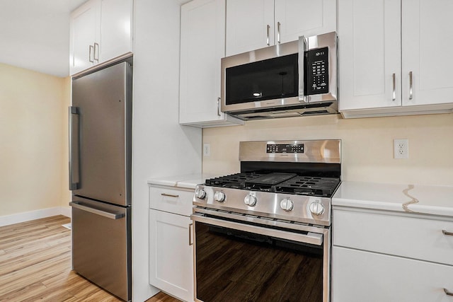 kitchen with white cabinets, light hardwood / wood-style floors, and appliances with stainless steel finishes