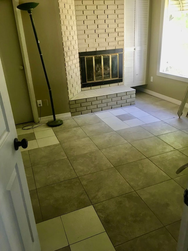 unfurnished living room with light tile patterned floors and a brick fireplace