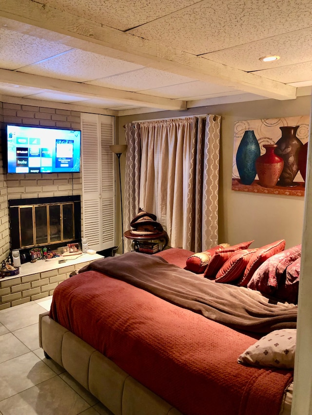 tiled bedroom with a fireplace and a drop ceiling