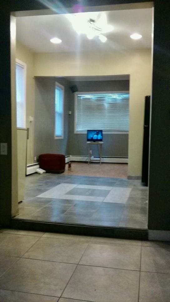 hallway with light tile patterned floors and a baseboard heating unit