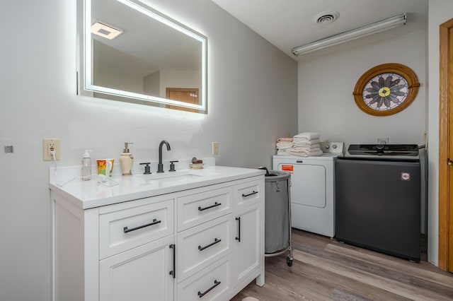 laundry room with sink, washer and dryer, and light hardwood / wood-style floors