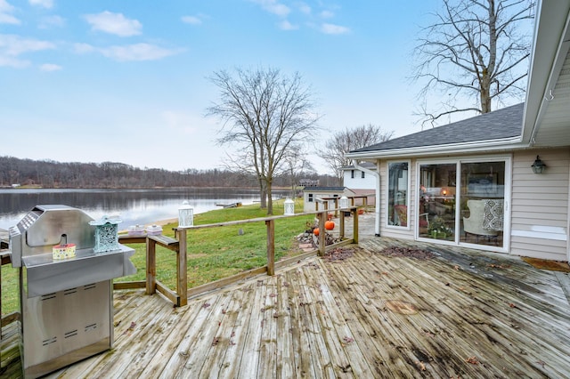 wooden terrace with a grill, a yard, and a water view