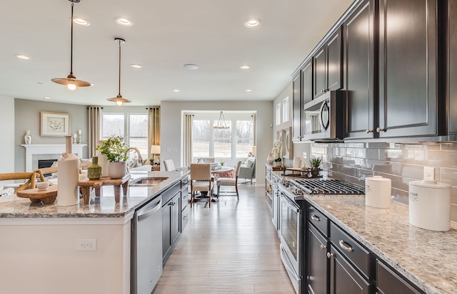 kitchen with light stone counters, pendant lighting, and appliances with stainless steel finishes